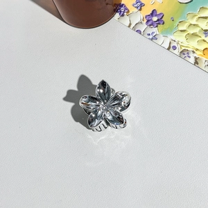 Gros plan d'une pince à cheveux fleur de frangipanier argentée avec finition miroir éclatante