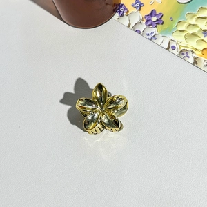 Vue détaillée d'une pince à cheveux fleur dorée avec une finition métallique brillante