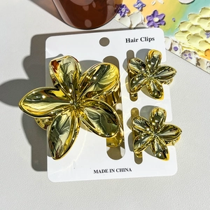 Détails d'un ensemble de 3 pinces à cheveux dorées en forme de fleurs de frangipanier