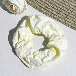 Close-up of pale yellow ribbed fabric hair scrunchie with soft vertical textures