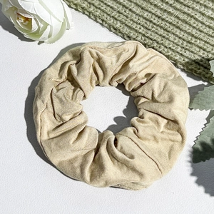 Detailed texture of the beige ribbed fabric scrunchie with elegant pleats and soft material