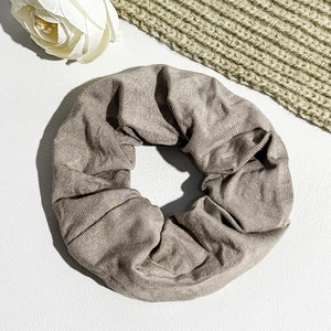 Close-up of brown ribbed fabric scrunchie with soft texture on white leather background