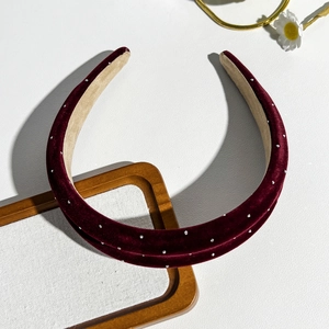 Detail of burgundy velvet headband with sparkly rhinestones on a minimalist background