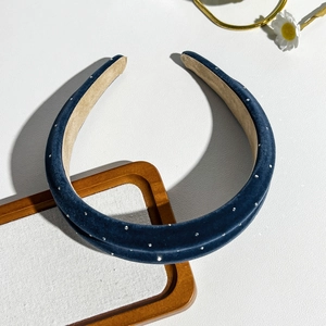 Detail of navy blue velvet headband with silver studs on a clean decorative background
