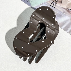 Detail of dark coffee heart-shaped hair claw with white polka dots and glossy finish