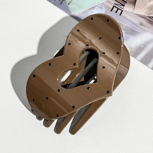 Detail of caramel heart hair claw clip with black polka dots and high gloss finish