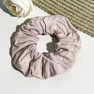 Detailed close-up of large pale pink hair scrunchie with subtle vertical ribbed texture
