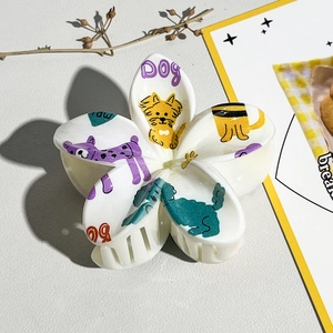 Détail de la pince à cheveux fleur avec motifs de chiens colorés et texte dog violet