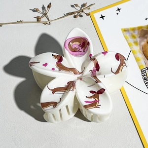 Détail d'une pince à cheveux fleur crème avec motif teckel mignon et imprimés de cœurs