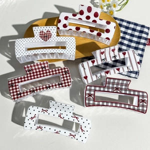 Detailed view of six vintage checkered and polka dot hair claws on a rustic wooden tray
