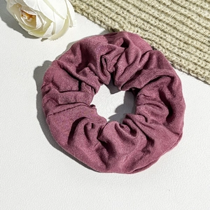 Detail of mauve oversized scrunchie with ribbed fabric texture and elastic design