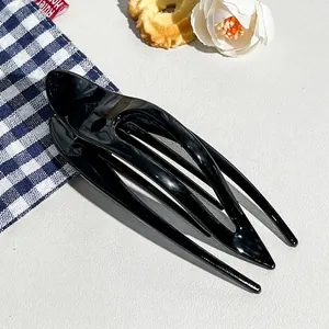 Close-up of a large glossy black hair claw clip with multi-tooth design on a white background
