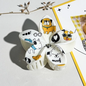Détail de la pince à cheveux fleur blanche avec imprimés chiens et texte décoratif WOOF
