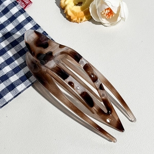Detail of leopard print hair clip with transparent texture on white leather background