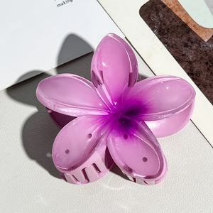 Detailed close-up of a gradient purple resin plumeria hair claw on a textured background