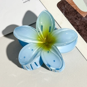 Close-up of blue and yellow frangipani flower hair claw on a premium textured background