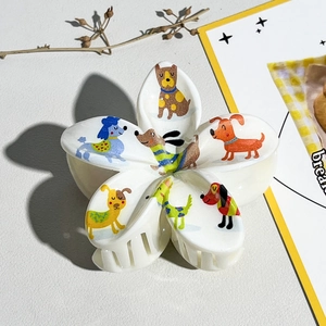 Détail d'une pince à cheveux en forme de fleur blanche avec illustrations de chiens