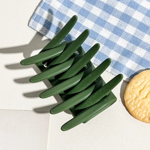 Detail shot of a matte dark green hair claw clip with large multi-tooth structure