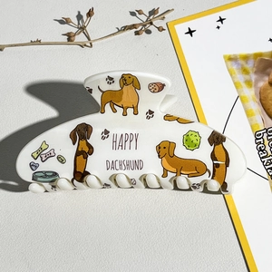 Détail de la pince à cheveux en acétate blanc avec imprimé UV de chiots teckels colorés