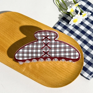 Close-up of retro checkered hair claw clip with red cross motifs on wooden tray