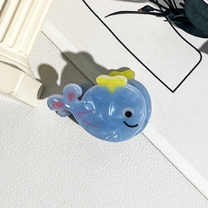 Gros plan d'une pince à cheveux baleine bleue avec texture marbre et détails jaunes
