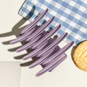 Detail of matte purple cross hair claw clip on blue checkered cloth background