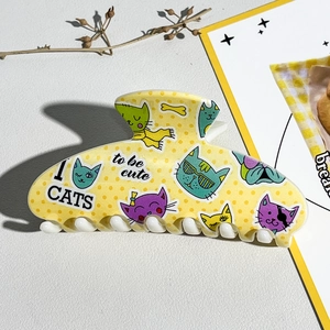 Détail d'une pince à cheveux jaune avec motif de chat dessin animé et impression UV