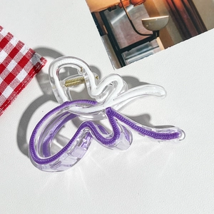 Détail de la grande pince à cheveux en acrylique avec rayures violettes et ressort doré