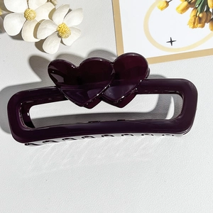 Detail of a deep purple rectangular hair claw with double heart design on white petals
