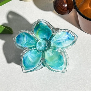 Macro detail of marble pattern flower hair claw with silver glitter and blue marble swirls