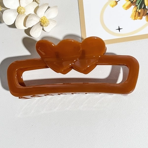 Detail view of a caramel brown rectangular hair claw clip with double heart cutouts