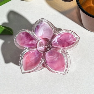 Detail of pink marble textured flower hair claw clip with glitter center on white leather