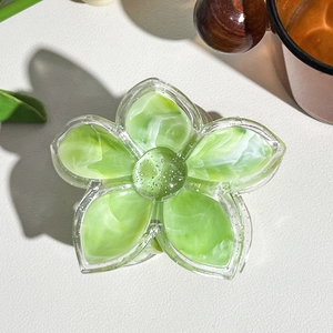 Detail shot of green marble pattern flower hair claw clip with silver glitter center