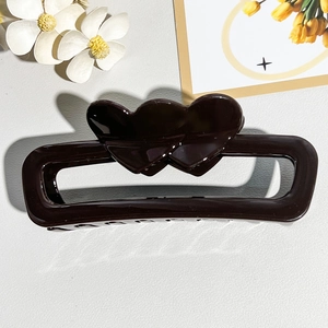 Close-up of a large dark brown hair claw clip with double heart hollow rectangular design