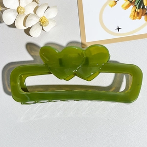 Top view of a grass green resin rectangular hair claw clip with double heart motif detail