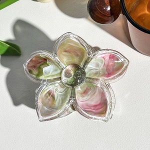 Close-up of a marble texture floral hair claw clip on a white leather surface