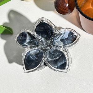 Macro shot of flower-shaped hair clip with black and white marble ink texture and silver glitter