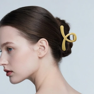 Elegant yellow resin hair claw clip in a minimalist twist design on model's updo hairstyle