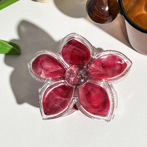 Macro detail of red marble texture flower hair claw with silver glitter floral center