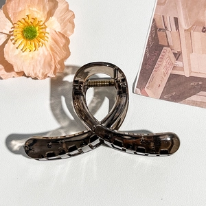 Detail view of a translucent smoke grey shark hair clip with a sleek matte finish
