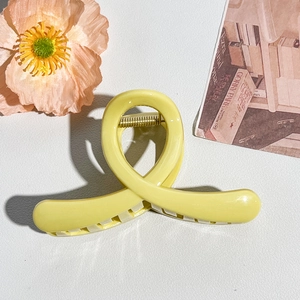 Pale yellow hair claw clip with smooth twisted design and gold spring on leather