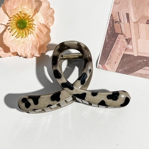 Detail of beige hair claw clip with black dalmatian spots and sturdy gold metal spring