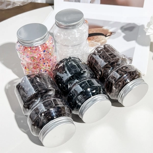 Five transparent jars with metal lids filled with colorful elastic hair ties in bulk
