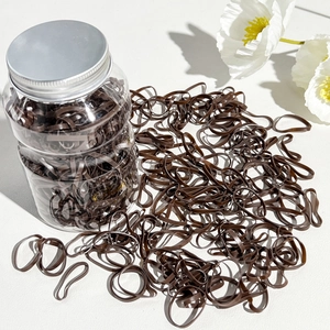 Detail of high-elastic dark brown hair ties in a clear bottle with silver lid