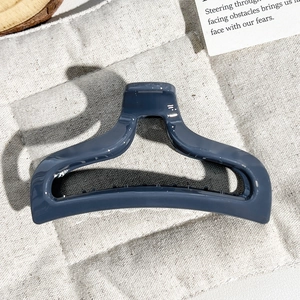 Detail of dark grey-blue PC fishtail hair claw with strong grip on beige linen background