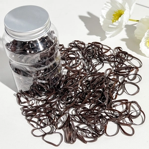 Detailed view of coffee-colored high-elasticity hair ties inside a clear storage jar
