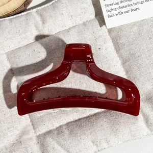 Close-up of translucent burgundy fish-tail hair claw with minimalist hollow geometric design