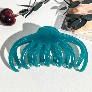 Dettaglio di una grande pinza per capelli a polpo blu petrolio per capelli folti su pelle