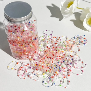 Detail of colorful elastic hair bands with polka dots in a clear jar with a floral background