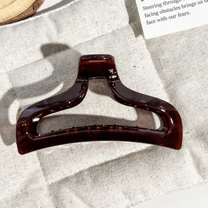 Detailed view of dark brown tortoiseshell hair claw clip on quilted beige fabric